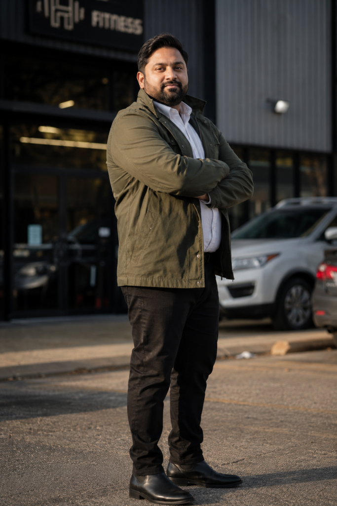 Olive Utility Jacket Over a White Oxford Shirt With Black Straight-Leg Trousers and Black Boots