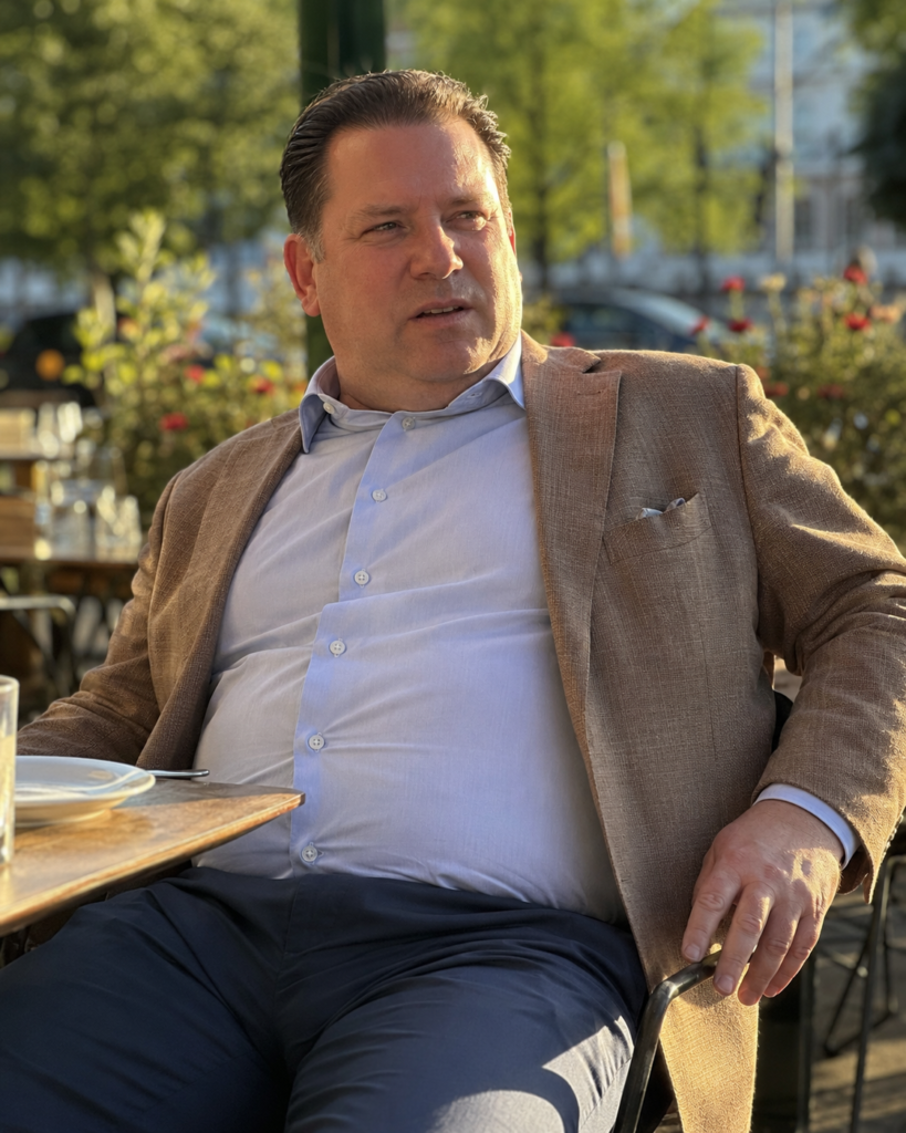  Slim Navy Trousers With a Fitted Light Blue Oxford Shirt and a Tan Unstructured Blazer